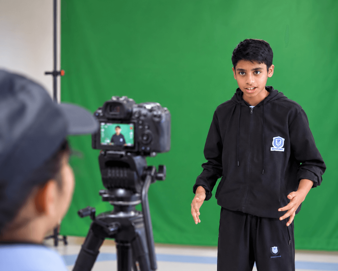 A student presenting a project while a classmate records him